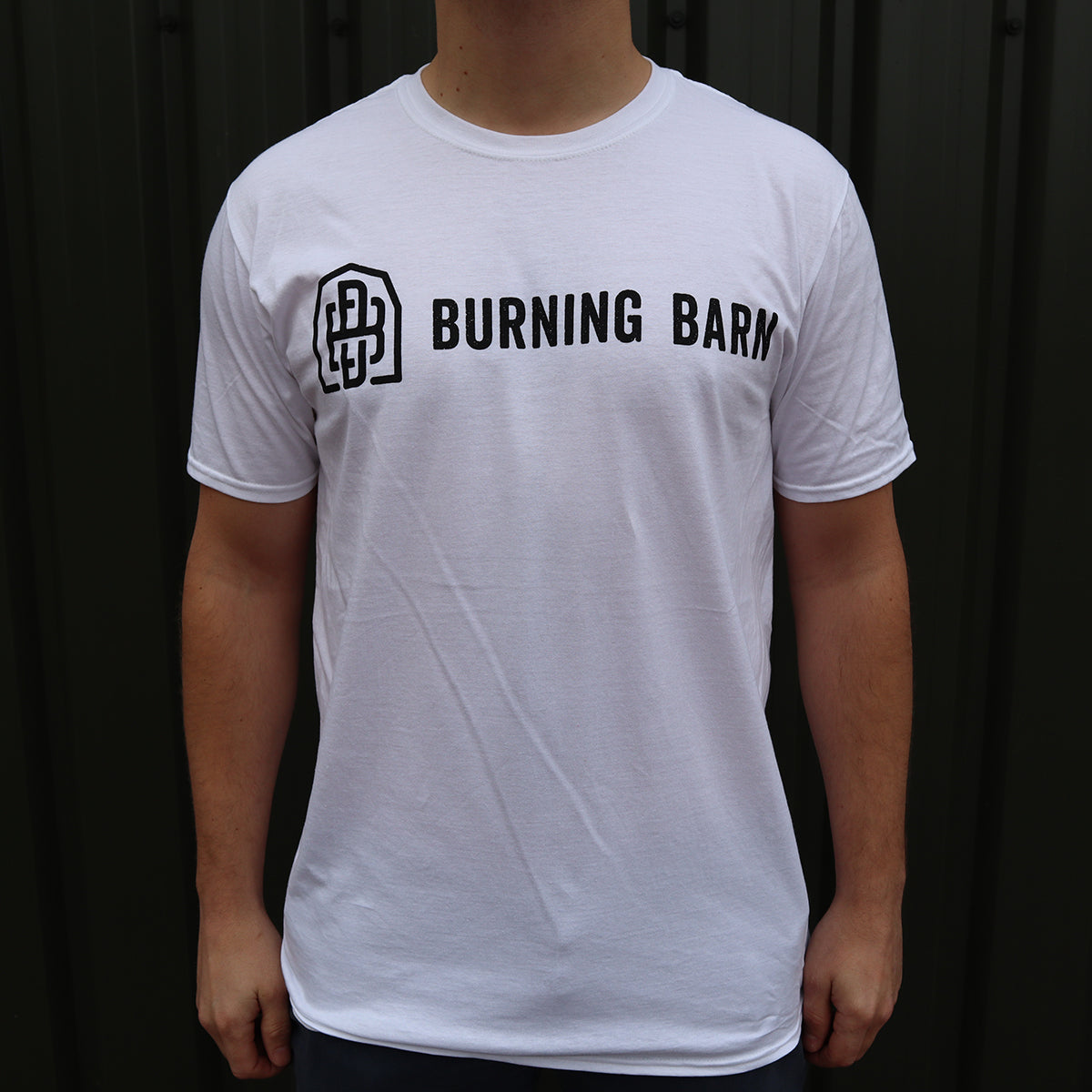 Person wearing a white t-shirt with the Burning Barn logo on it - view of the front