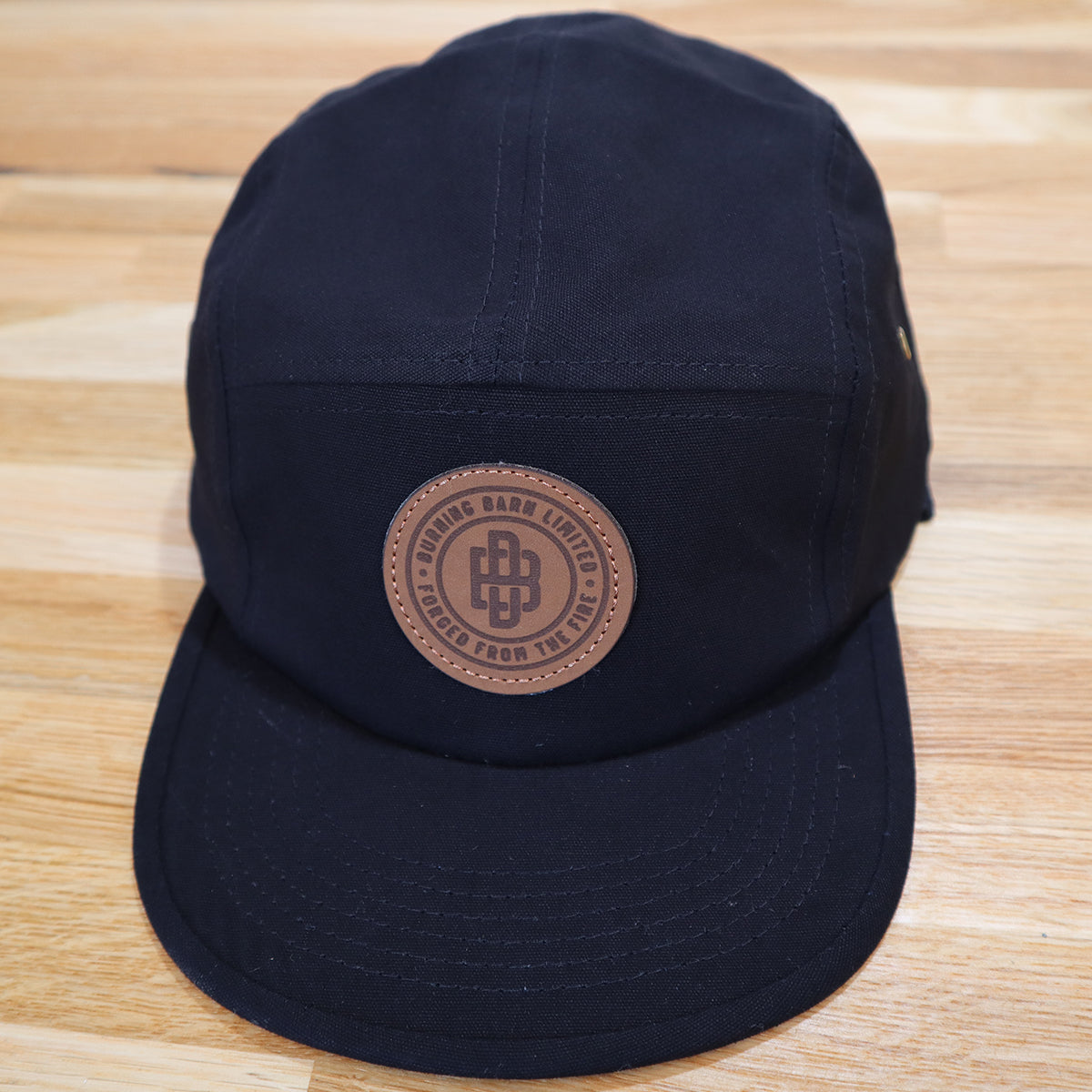Front view of a black cap with Burning Barn logo imprinted on the front