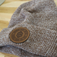 Close-up of oatmeal coloured beanie with Burning Barn logo on it